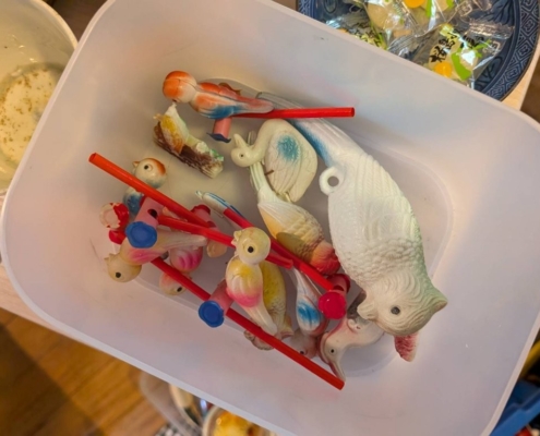 戦前から昭和期にかけて作られたセルロイド製の鳥や魚のオモチャが容器にまとめられている様子。横浜市栄区の空き家整理で発見された玩具。