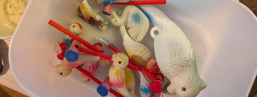 戦前から昭和期にかけて作られたセルロイド製の鳥や魚のオモチャが容器にまとめられている様子。横浜市栄区の空き家整理で発見された玩具。