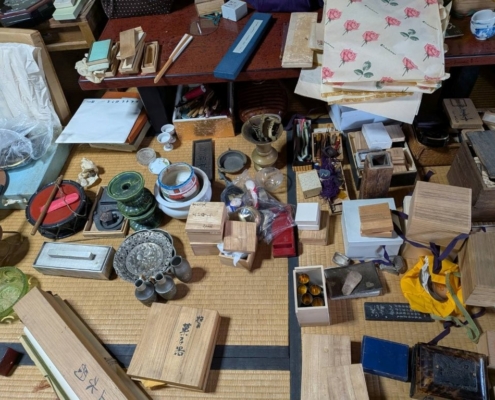 造り酒屋で使われていたと見られる盃や茶道具、桐箱や仕覆が点数ごとに確認できる実家整理中の査定風景。