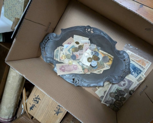 段ボール箱の中でトレーにまとめられた古銭と紙幣の混在状態の写真