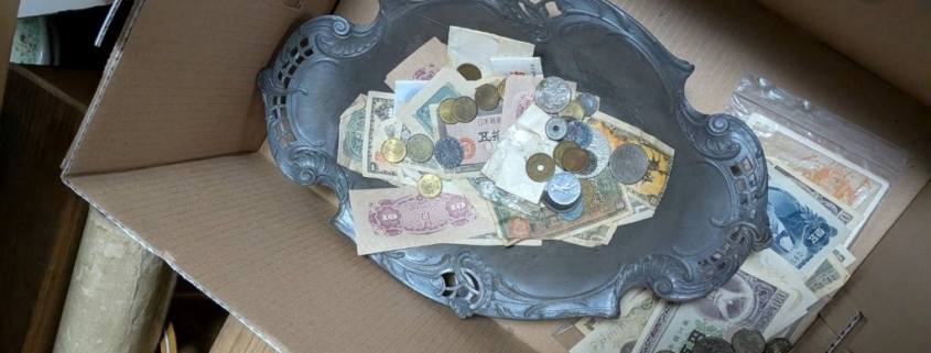 段ボール箱の中でトレーにまとめられた古銭と紙幣の混在状態の写真